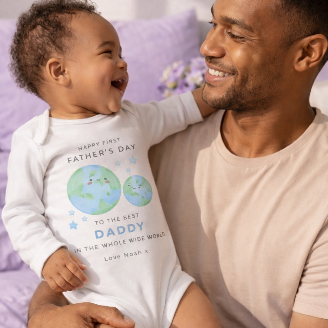 personalised sleepsuit celebrating first father's day, being held by his Dad