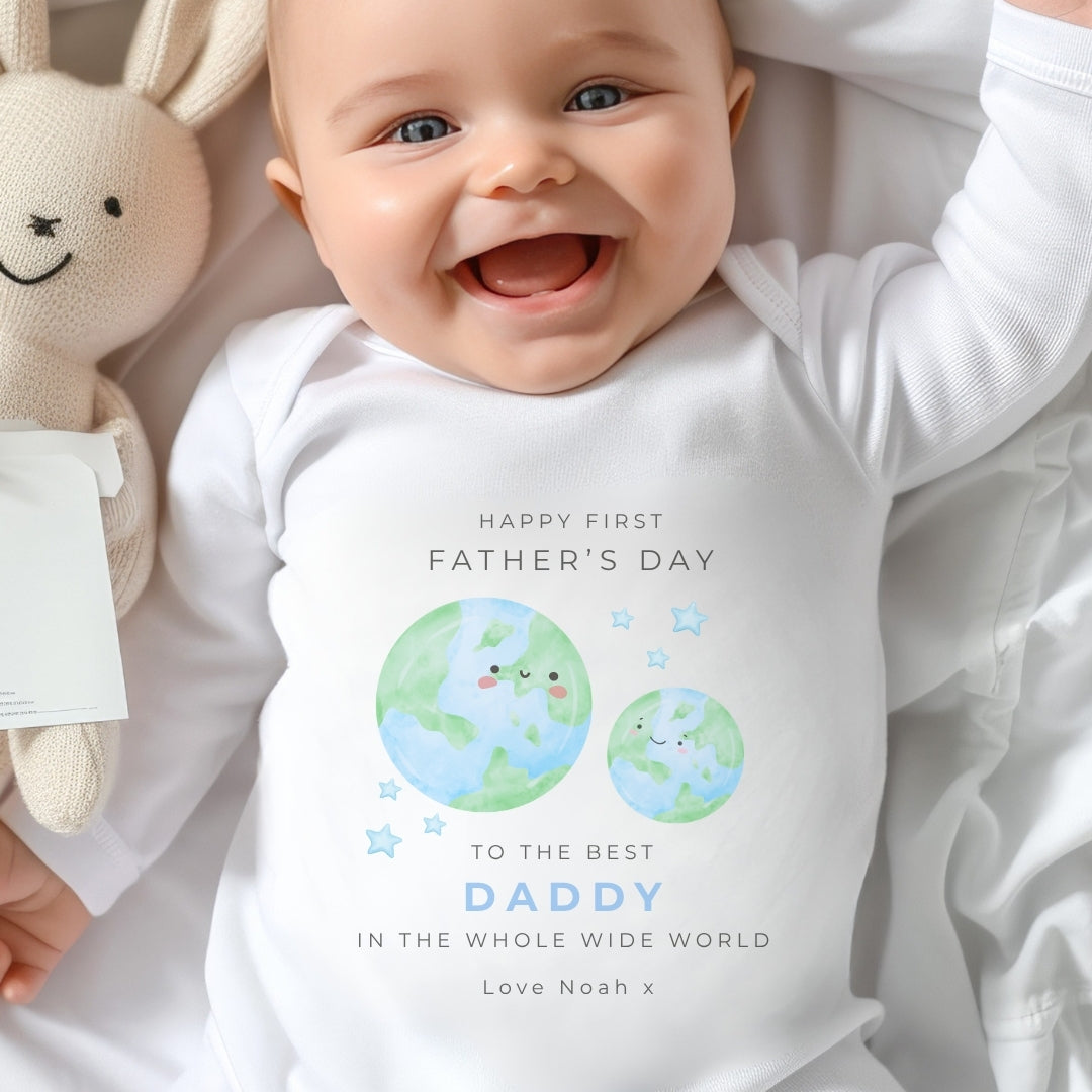 Baby in a personalised sleepsuit celebrating first father's day, featuring a heartfelt message and cute planet design.